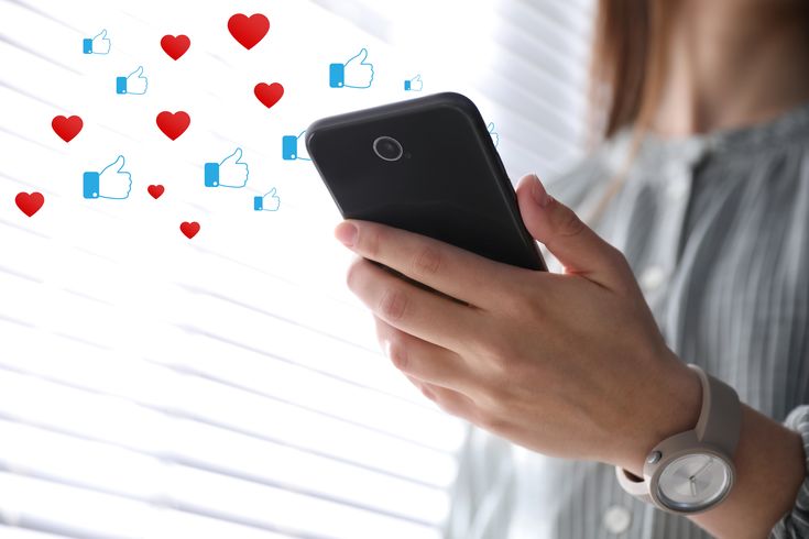 phone with love heart and like emojis above